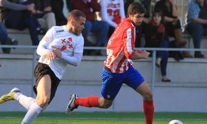 Nacho Monsalve, del Atlético C, se lleva el esférico en pugna con un jugador del Carabanchel y ante la mirada de Juanfri