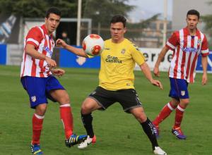 Vicente, jugador del Atlético B, da un pase en el partido contra Las Palmas Atlético ante la oposición del canario Roque