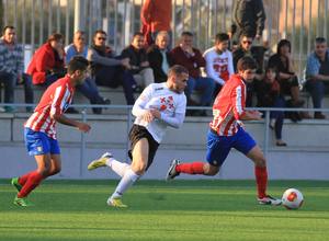 Nacho Monsalve, del Atlético C, se lleva el esférico en pugna con un jugador del Carabanchel y ante la mirada de Juanfri